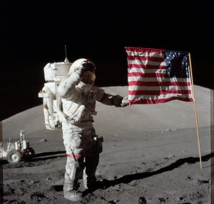 Astronaut Eugene A. Cernan, Apollo 17 commander, is photographed next to the deployed United States flag during lunar surface 