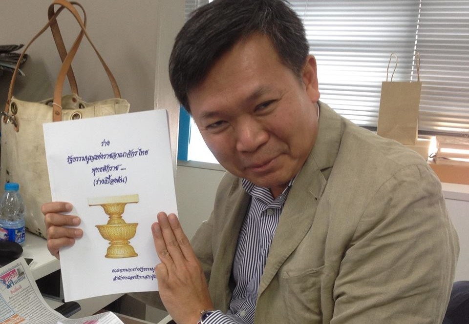 Pravit Rojanaphruk holding a copy of the draft constitution which some critics believe will reinforce military rule in Thailand. Pravit is seen flashing the three-finger sign which is also a symbol of protest used by pro-democracy forces in Thailand. Source: Facebook