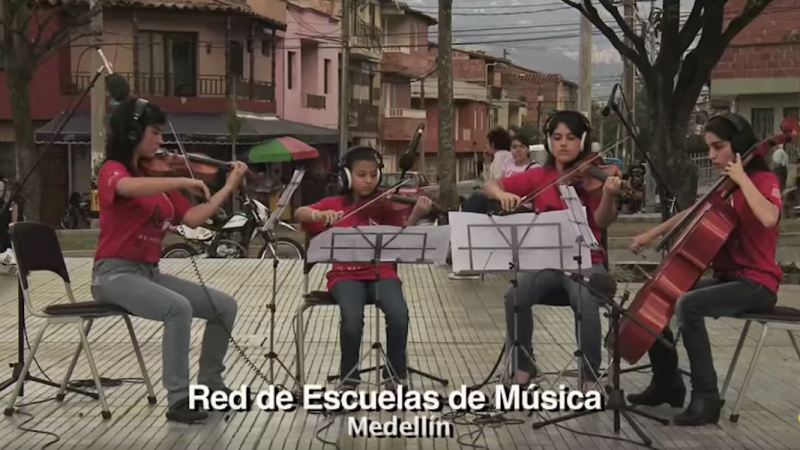 Cuatro miembros de la Red de Escuelas de Música de Medellín tocan parte de "La Tierra del Olvido" desde una de las comunas de Medellín. Captura de pantalla del video disponible en la cuenta de YouTube de Playing for a Change. 