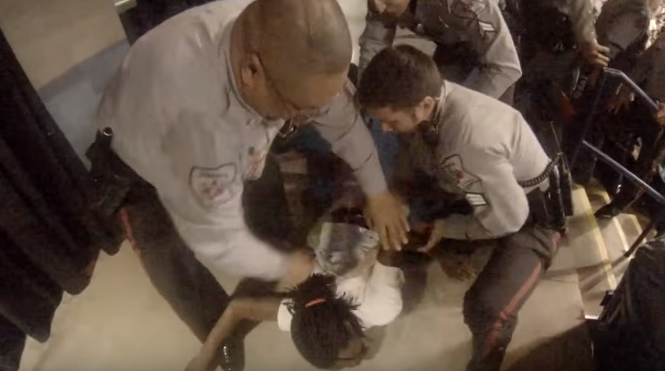 A screenshot of footage, uploaded to YouTube by Storyful, of a protester who was assaulted by a Donald Trump supporter being restrained by police at a rally in North Carolina. 
