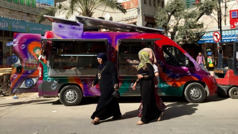 Palestinian women walk past "Qitar Ata'am", which translates into "the Food Train," the first food truck in Ramallah. Credit: Dalia Hatuqa 