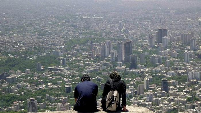 A young couple sit atop a hill overlooking Tehran. Image from ICHRI. 