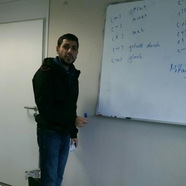 Hassan stands in front of a whiteboard during German language classes in his new hometown. Credit: Hassan Jamous
