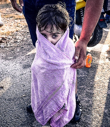 Una niña intenta entrar en calor a su llegada a las costas griegas tras un peligroso viaje en una patera sobrecargada, 15 de agosto de 2015. Foto de Freedom House en Flickr, de dominio público