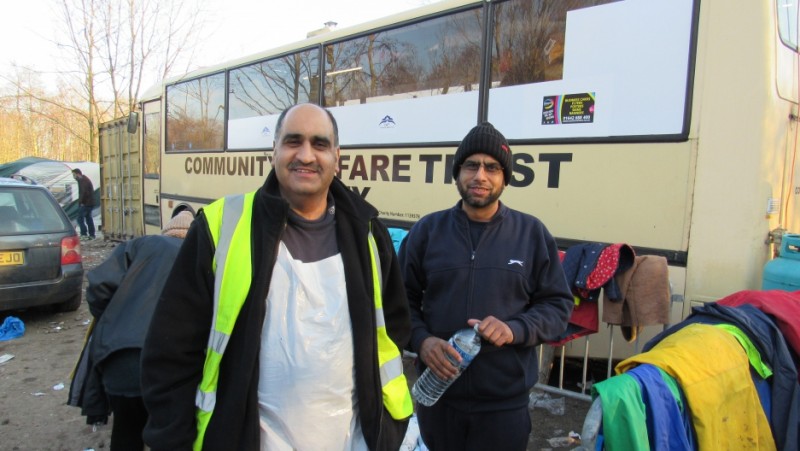 Ghafoor Hussain and his brother Fazel stand outside Ghafoor's bus-turned-mobile kitchen. They're supplying 3,000 hot meals a day, and 10,000 cups of tea. Credit: Adeline Sire. Used with PRI's permission
