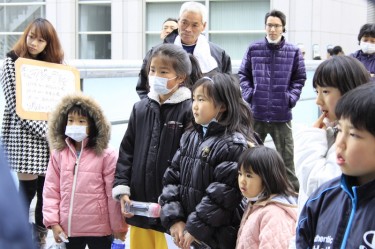 Children evacuated from the town Futaba, enjoying a magic show in front of the Saitama Super Arena. Saitama, Japan. 27/03/2011. Image from Demotix