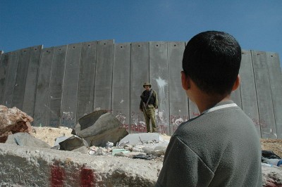 Boy and soldier in front of Israeli wall - West Bank via Wikipédia CC-BY-2.0  