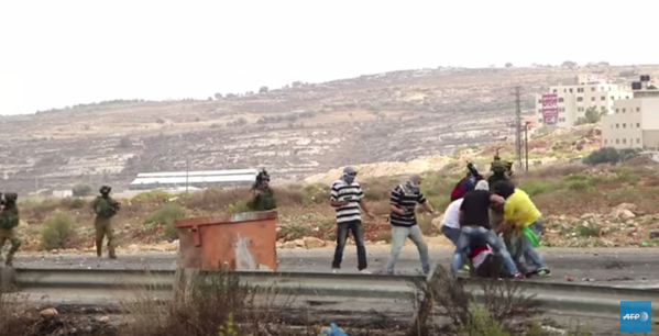 The undercover Israeli protesters seen pointing guns at Palestinian stone-throwers in a still from a video taken by AFP and shared on YouTube today. Still shared by @joeyayoub on Twitter 