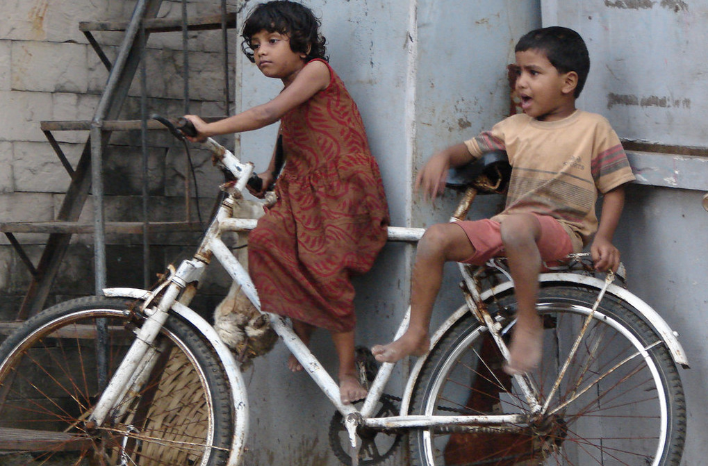 Indian Kids on the street wtih a cycle. Often traditional gender roles are imposed on them (not in this case). Image from Flickr by Harini Calamur . BY-NC-ND 2.0