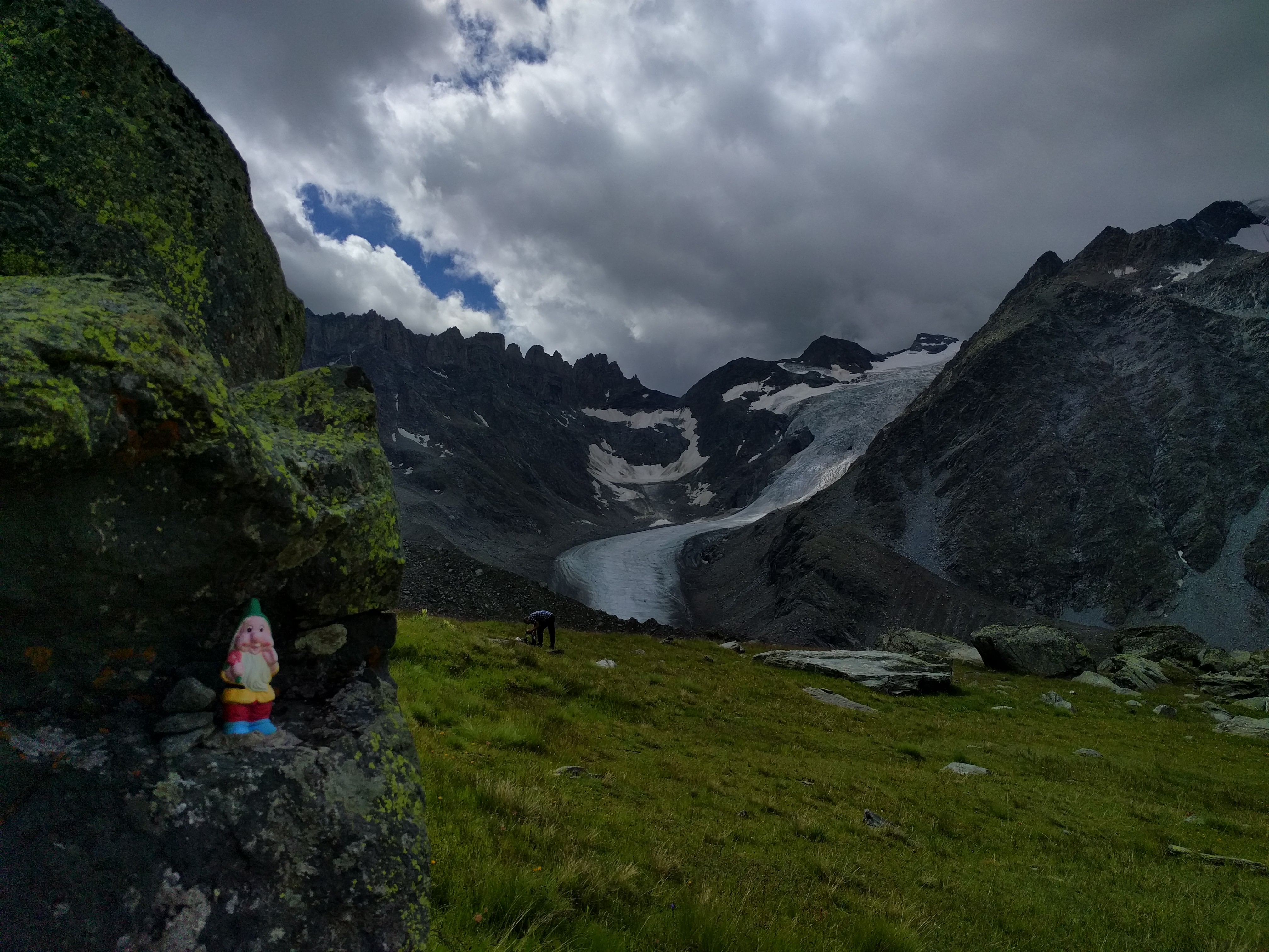 Statue de gnome sous une pierre, homme fouillant dans son sace, glacier de Valsoret